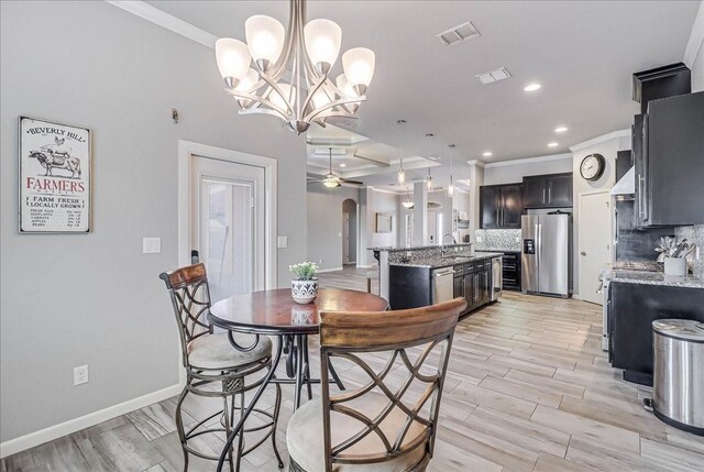 dining area with crown molding, ceiling fan, a chandelier, baseboards, and light wood-style floors