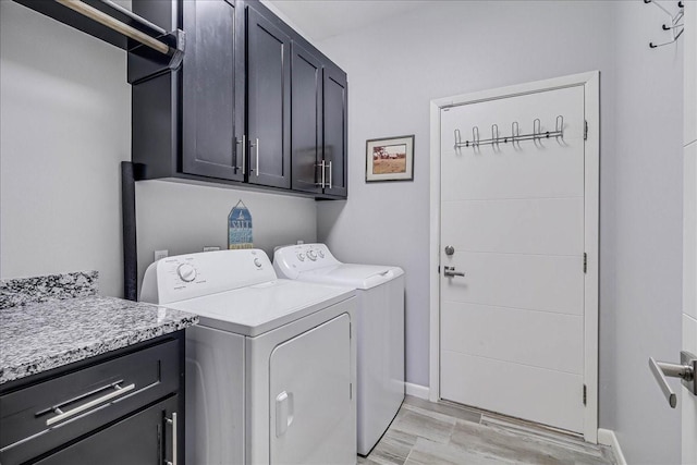 clothes washing area featuring cabinet space, independent washer and dryer, light wood-type flooring, and baseboards