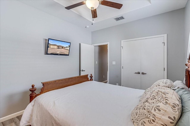 bedroom with a closet, ceiling fan, wood finished floors, and baseboards