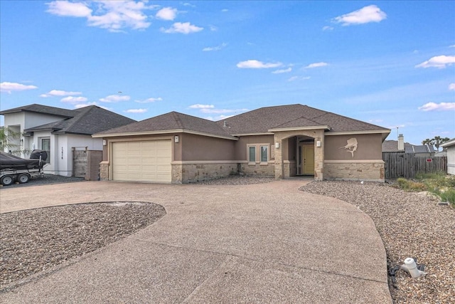 view of front of house featuring stone siding, stucco siding, driveway, and an attached garage