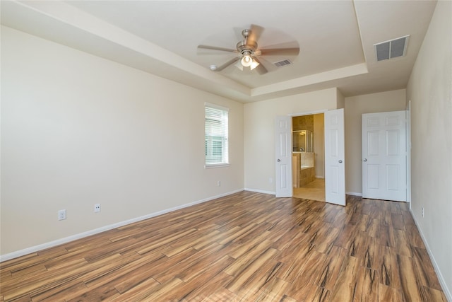 8919 Inglebrook Ln, Houston, TX 77083 - unfurnished bedroom featuring a tray ceiling, wood finished floors, baseboards, ensuite bath, and ceiling fan