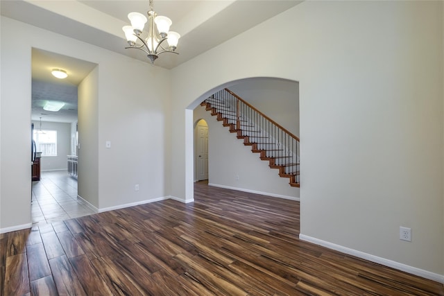 8919 Inglebrook Ln, Houston, TX 77083 - spare room featuring a chandelier, dark wood-style flooring, arched walkways, stairs, and baseboards