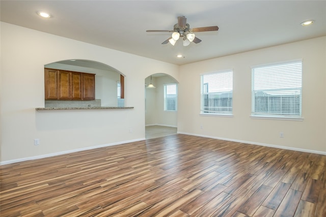 8919 Inglebrook Ln, Houston, TX 77083 - unfurnished living room with ceiling fan, arched walkways, dark wood-type flooring, recessed lighting, and baseboards