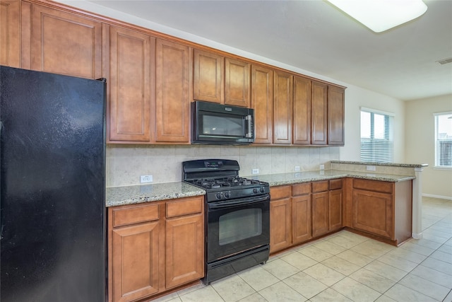 8919 Inglebrook Ln, Houston, TX 77083 - kitchen with black appliances, a peninsula, light tile patterned floors, brown cabinetry, and light stone counters