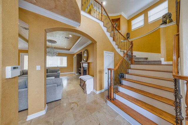 8606 Argentina St, Jersey Village, TX 77040 - staircase with arched walkways, ornamental molding, baseboards, a chandelier, and a fireplace