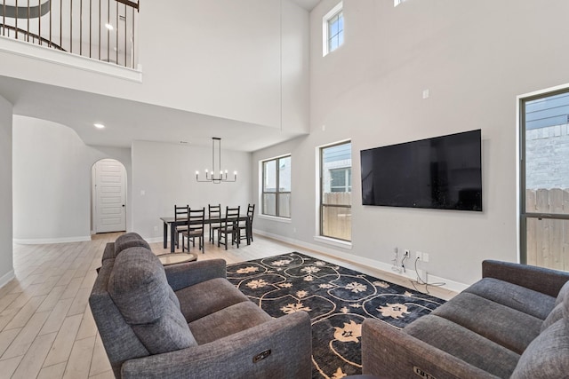 7010 Grassland Vista Ln, Katy, TX 77493 - living room featuring arched walkways, wood finished floors, a chandelier, and a high ceiling