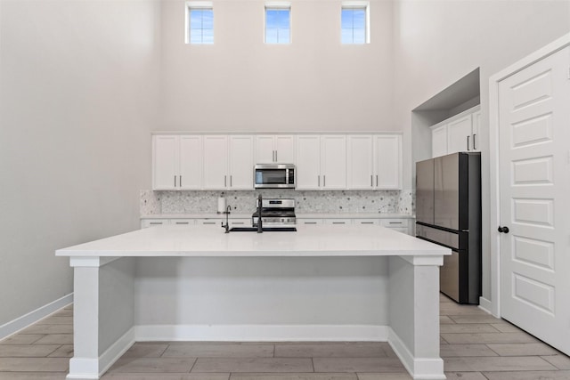 7010 Grassland Vista Ln, Katy, TX 77493 - kitchen featuring stainless steel appliances, backsplash, light wood-type flooring, white cabinets, and a towering ceiling