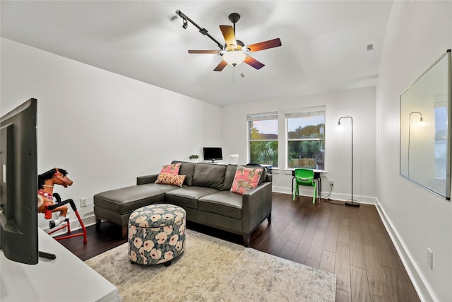 living area with ceiling fan, baseboards, and dark wood-type flooring
