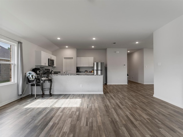 2715 Marguerite St, Bay City, TX 77414 - kitchen featuring appliances with stainless steel finishes, wood finished floors, white cabinetry, stone countertops, and a peninsula