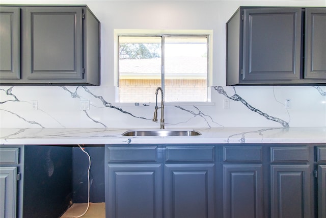 2402 N Ferrisburg Ct, Sugar Land, TX 77478 - kitchen with a sink, decorative backsplash, light stone counters, and gray cabinetry