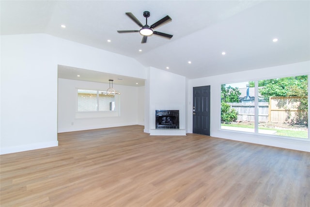 2402 N Ferrisburg Ct, Sugar Land, TX 77478 - unfurnished living room with vaulted ceiling, light wood-style flooring, a fireplace with raised hearth, a ceiling fan, and a chandelier