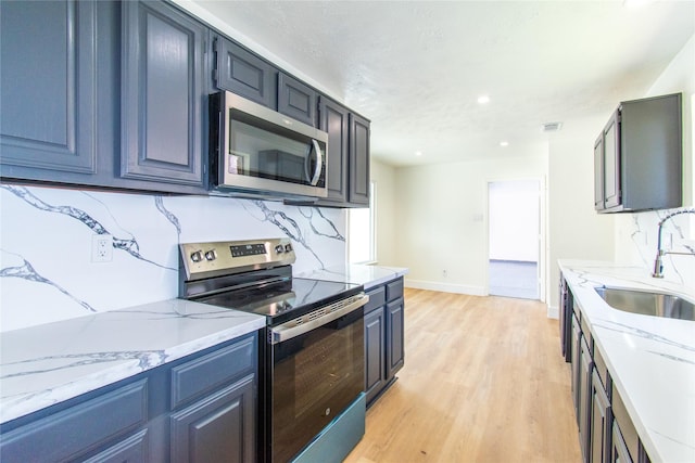 2402 N Ferrisburg Ct, Sugar Land, TX 77478 - kitchen with stainless steel appliances, a sink, light wood-style floors, light stone countertops, and tasteful backsplash
