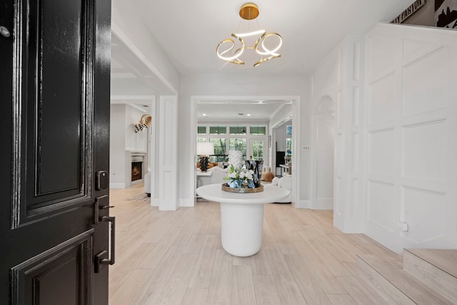3702 Deerbend Ct, Spring, TX 77386 - foyer entrance featuring a chandelier, baseboards, light wood finished floors, and a lit fireplace