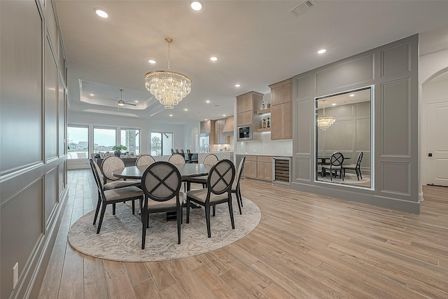 10615 Painted Crescent Ct, Cypress, TX 77433 - dining room with a chandelier, beverage cooler, a raised ceiling, light wood finished floors, and recessed lighting