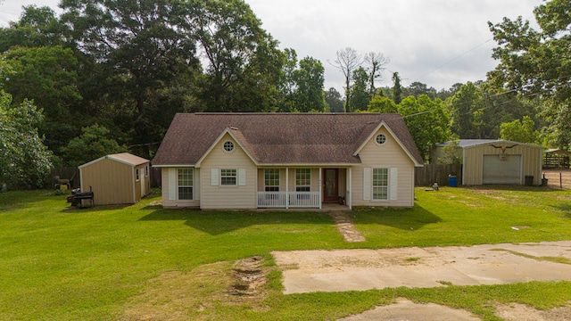 11664 Fm 92, Silsbee, TX 77656 - view of front of house featuring an outdoor structure, covered porch, a detached garage, a front lawn, and roof with shingles