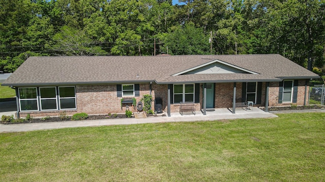 1191 Barnum Blvd, Corrigan, TX 75939 - ranch-style house featuring a shingled roof, brick siding, a front lawn, and a porch
