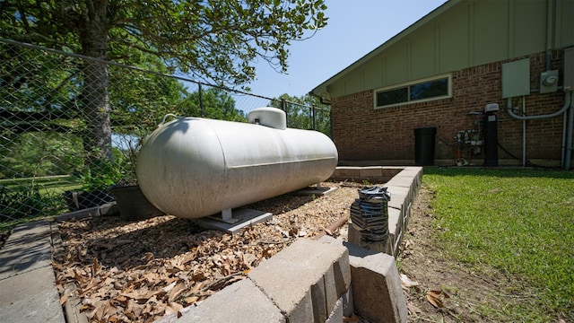 1191 Barnum Blvd, Corrigan, TX 75939 - exterior view of gas tank, electric meter, board and batten siding, fence, and brick siding