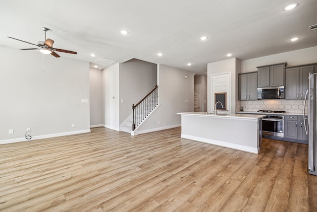 10292 Bayou Oaks Dr, Conroe, TX 77385 - kitchen with appliances with stainless steel finishes, open floor plan, gray cabinetry, backsplash, and a sink