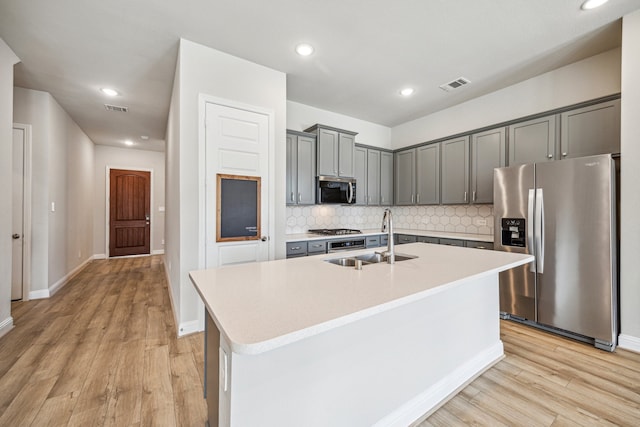 10292 Bayou Oaks Dr, Conroe, TX 77385 - kitchen with appliances with stainless steel finishes, a sink, gray cabinets, light wood-style flooring, and backsplash