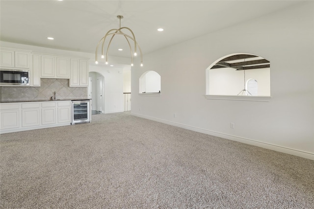 18011 Stari Most Ln, Houston, TX 77044 - kitchen featuring wine cooler, stainless steel microwave, carpet floors, arched walkways, and a sink