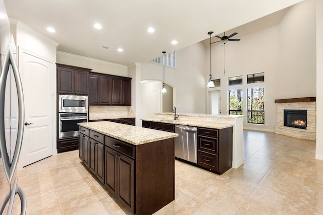 32 Evangeline Blvd, Conroe, TX 77304 - kitchen with appliances with stainless steel finishes, an island with sink, ceiling fan, decorative backsplash, and open floor plan