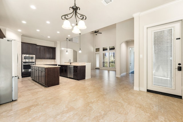 32 Evangeline Blvd, Conroe, TX 77304 - kitchen featuring arched walkways, appliances with stainless steel finishes, an island with sink, a ceiling fan, and dark brown cabinets