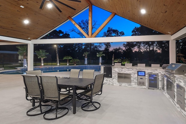 15232 Saddlewood Dr, Conroe, TX 77384 - patio at night featuring an outdoor kitchen, a ceiling fan, fence, a grill, and outdoor dining area