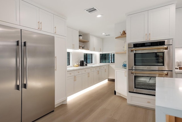 15232 Saddlewood Dr, Conroe, TX 77384 - kitchen with stainless steel appliances, open shelves, light wood-type flooring, white cabinetry, and light countertops