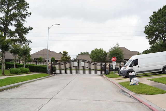 16019 Summerville Lake Dr, Tomball, TX 77377 - view of concrete road with sidewalks, traffic signs, a gate, and curbs