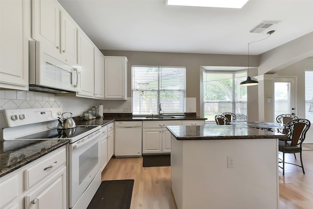 17006 Valley Palms Dr, Spring, TX 77379 - kitchen featuring white appliances, a kitchen island, light wood-style flooring, decorative backsplash, and white cabinetry