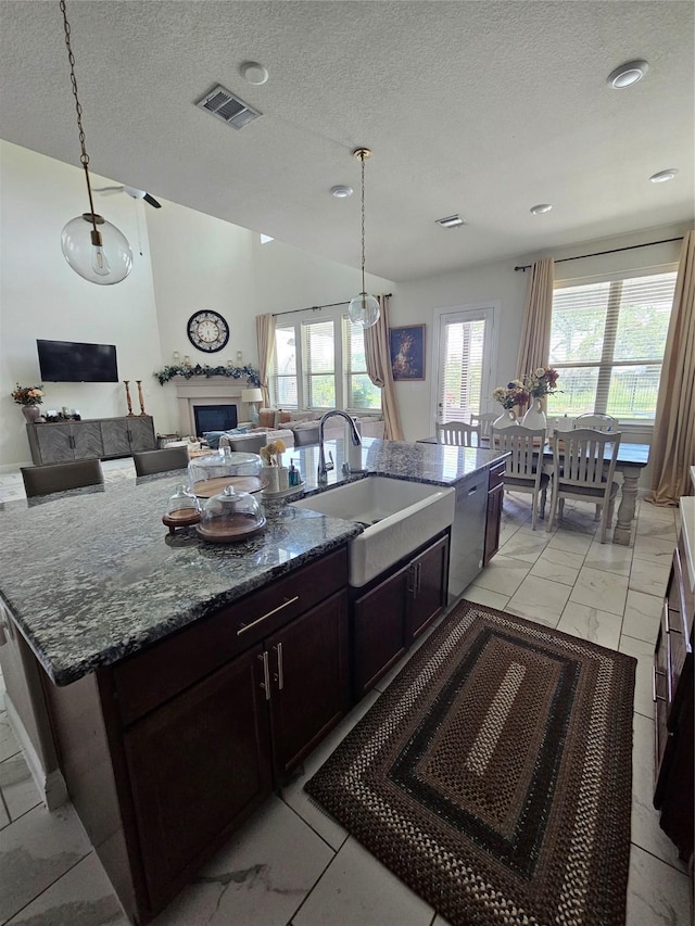 1013 Goose Creek St, Webster, TX 77598 - kitchen with light marble finish flooring, a fireplace, pendant lighting, dark stone countertops, and a textured ceiling