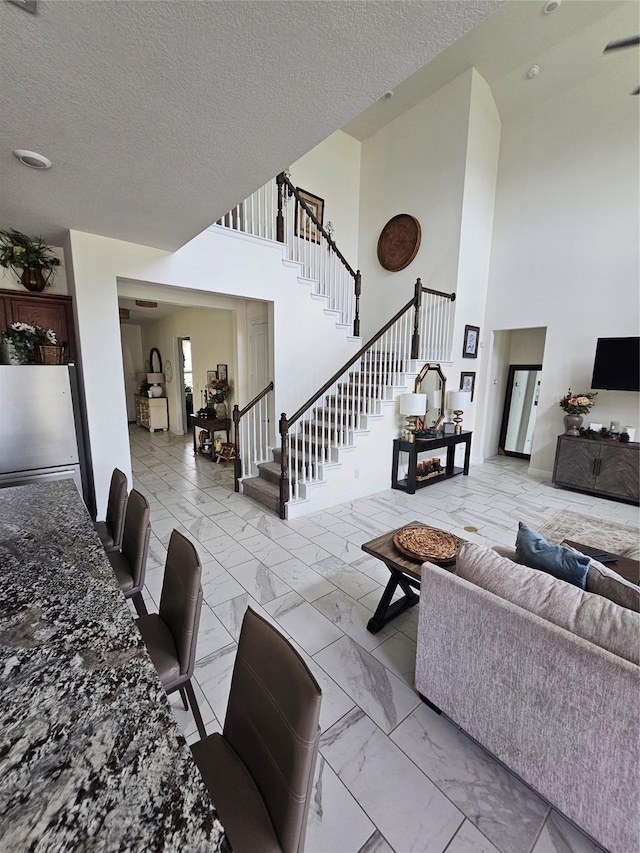 1013 Goose Creek St, Webster, TX 77598 - living area featuring marble look tiles, stairway, a towering ceiling, and a textured ceiling