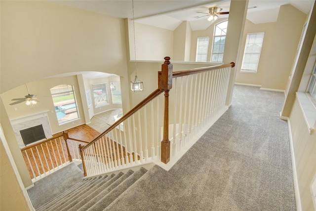 10900 Spruce Dr N, La Porte, TX 77571 - stairs with a ceiling fan, carpet flooring, vaulted ceiling, a fireplace, and arched walkways