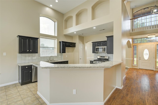 10900 Spruce Dr N, La Porte, TX 77571 - kitchen featuring appliances with stainless steel finishes, a high ceiling, arched walkways, dark cabinetry, and a sink