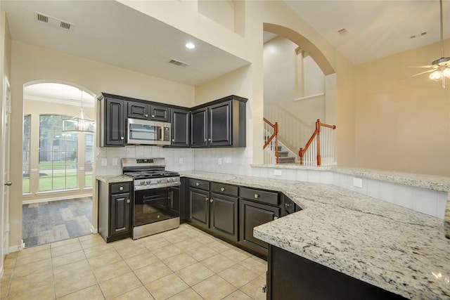 10900 Spruce Dr N, La Porte, TX 77571 - kitchen with appliances with stainless steel finishes, arched walkways, a ceiling fan, tasteful backsplash, and light stone countertops