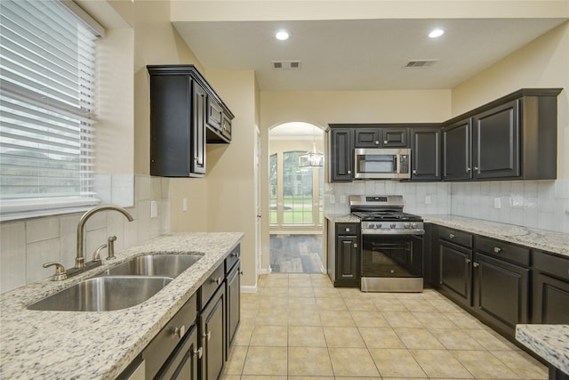 10900 Spruce Dr N, La Porte, TX 77571 - kitchen with stainless steel appliances, a sink, arched walkways, decorative backsplash, and recessed lighting