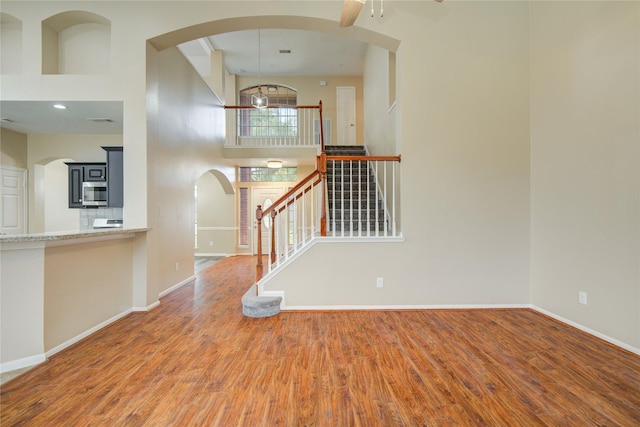 10900 Spruce Dr N, La Porte, TX 77571 - foyer entrance featuring wood finished floors, stairway, baseboards, arched walkways, and ceiling fan