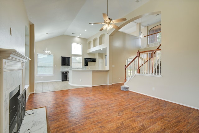 10900 Spruce Dr N, La Porte, TX 77571 - unfurnished living room featuring high vaulted ceiling, a high end fireplace, ceiling fan, light wood-type flooring, and stairway