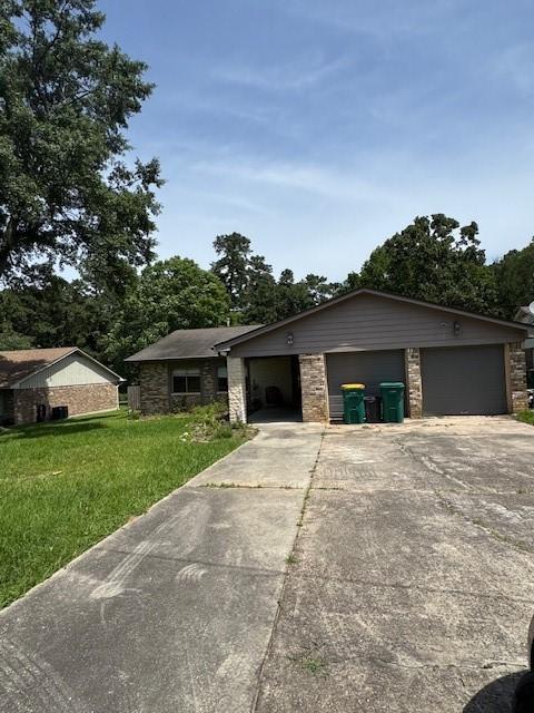 view of front facade with concrete driveway, an attached garage, a front lawn, and stone siding