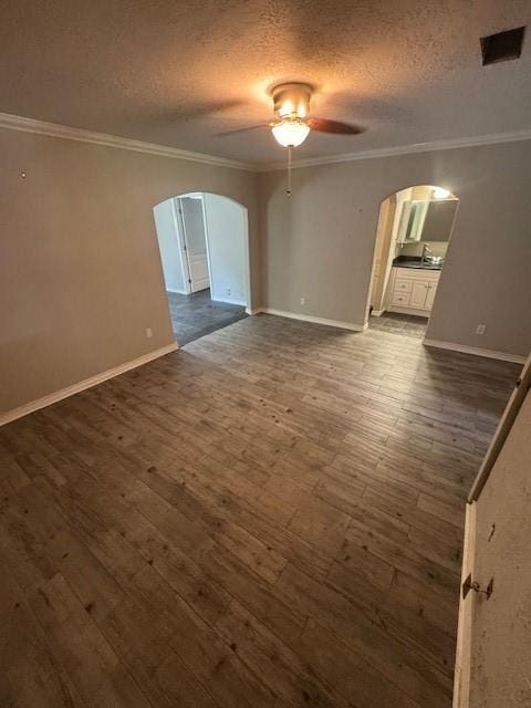 spare room featuring arched walkways, ceiling fan, dark wood-style floors, ornamental molding, and a textured ceiling