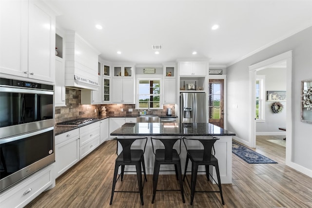 3785 County Road 405, Anderson, TX 77830 - kitchen with stainless steel appliances, backsplash, white cabinetry, a breakfast bar, and crown molding