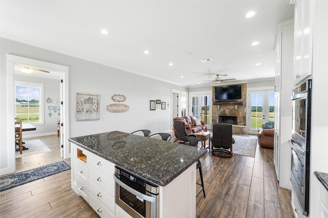 3785 County Road 405, Anderson, TX 77830 - kitchen featuring ceiling fan, a stone fireplace, a breakfast bar, stainless steel double oven, and recessed lighting
