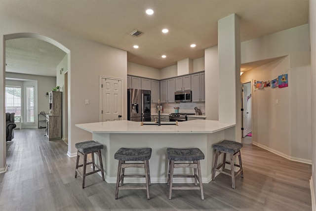 3729 Breckenridge Dr, Montgomery, TX 77356 - kitchen featuring appliances with stainless steel finishes, a sink, gray cabinets, arched walkways, and light wood finished floors
