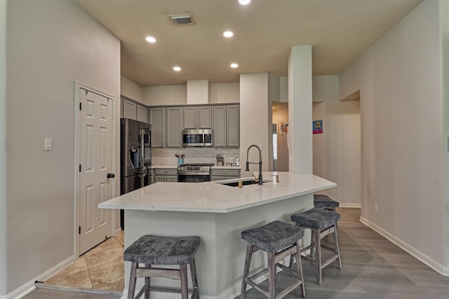 3729 Breckenridge Dr, Montgomery, TX 77356 - kitchen with stainless steel appliances, a sink, gray cabinets, a kitchen breakfast bar, and baseboards