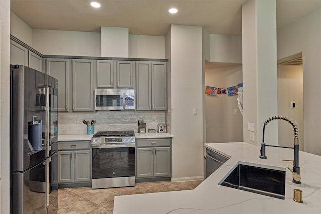 3729 Breckenridge Dr, Montgomery, TX 77356 - kitchen featuring appliances with stainless steel finishes, gray cabinetry, a sink, tasteful backsplash, and recessed lighting