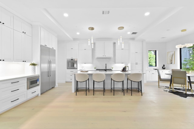 5115 Maple St, Houston, TX 77401 - kitchen with built in appliances, white cabinetry, a breakfast bar area, recessed lighting, and a kitchen island with sink