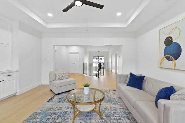 5115 Maple St, Houston, TX 77401 - living area with light wood-style floors, a ceiling fan, a tray ceiling, and baseboards