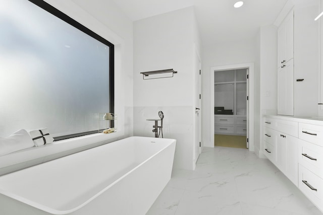 5115 Maple St, Houston, TX 77401 - bathroom featuring marble look tiles, a freestanding bath, vanity, recessed lighting, and a spacious closet