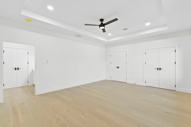 5115 Maple St, Houston, TX 77401 - unfurnished bedroom featuring a tray ceiling, light wood-type flooring, recessed lighting, multiple closets, and baseboards