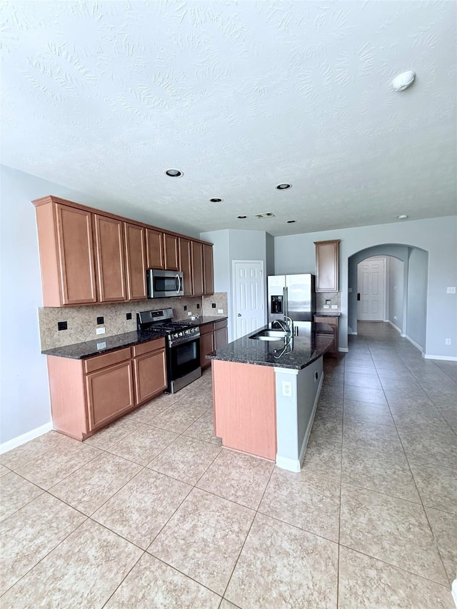13938 Kenswick Key Ln, Houston, TX 77047 - kitchen with stainless steel appliances, arched walkways, a sink, tasteful backsplash, and baseboards